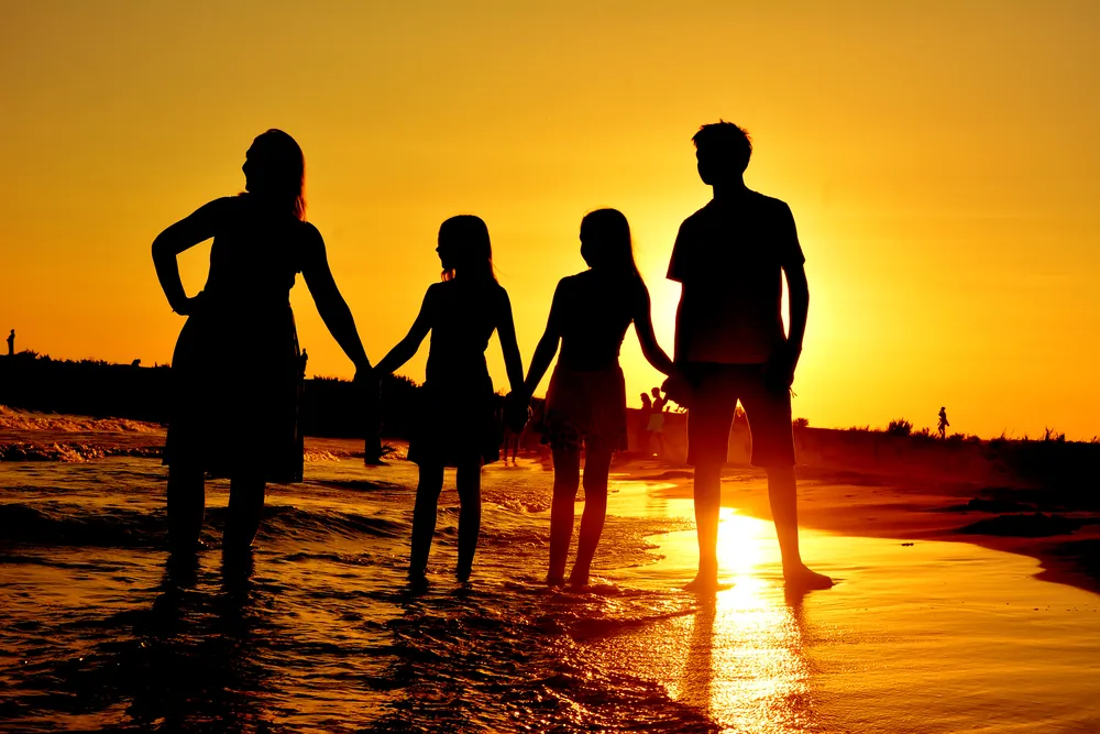 Familie als Silhouette Hand in Hand im Sonnenuntergang am Meer
