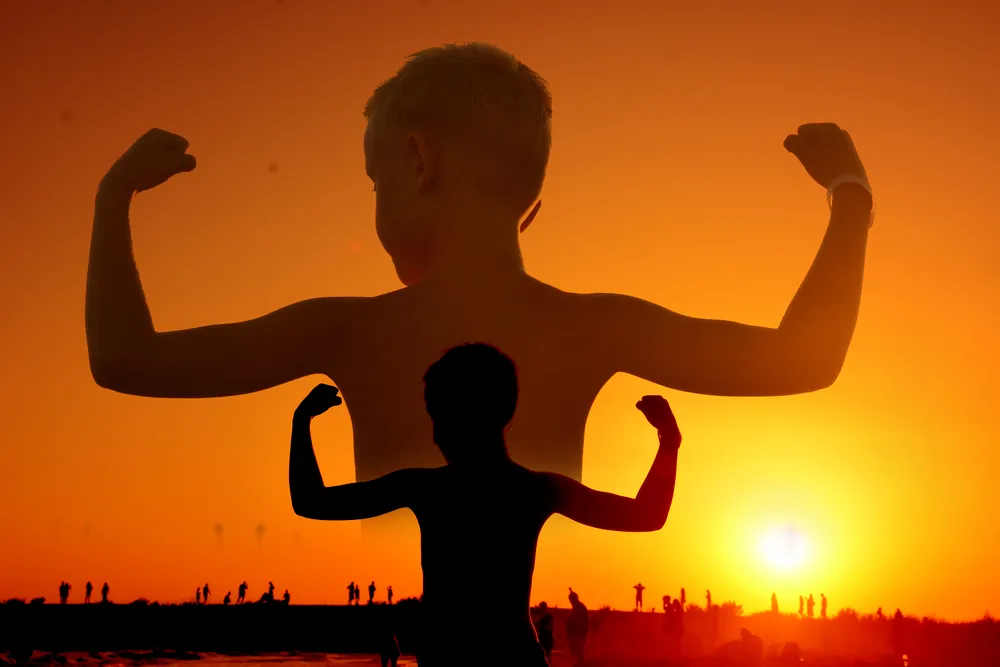 Silhouette eines Jungen im Muskel-Pose vor Sonnenuntergang