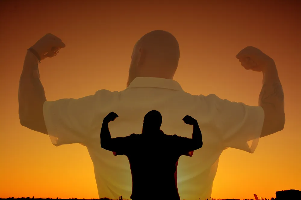 Silhouette in Muskel-Pose vor glühendem Abendhimmel