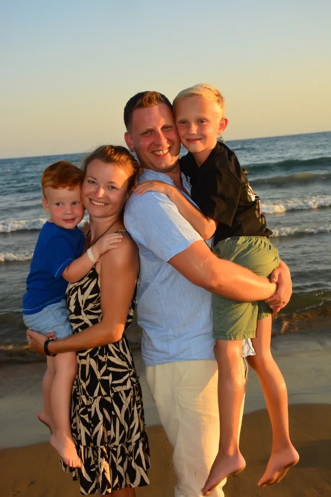 Familie zu fünft am Strand im Abendlicht, Hochformat