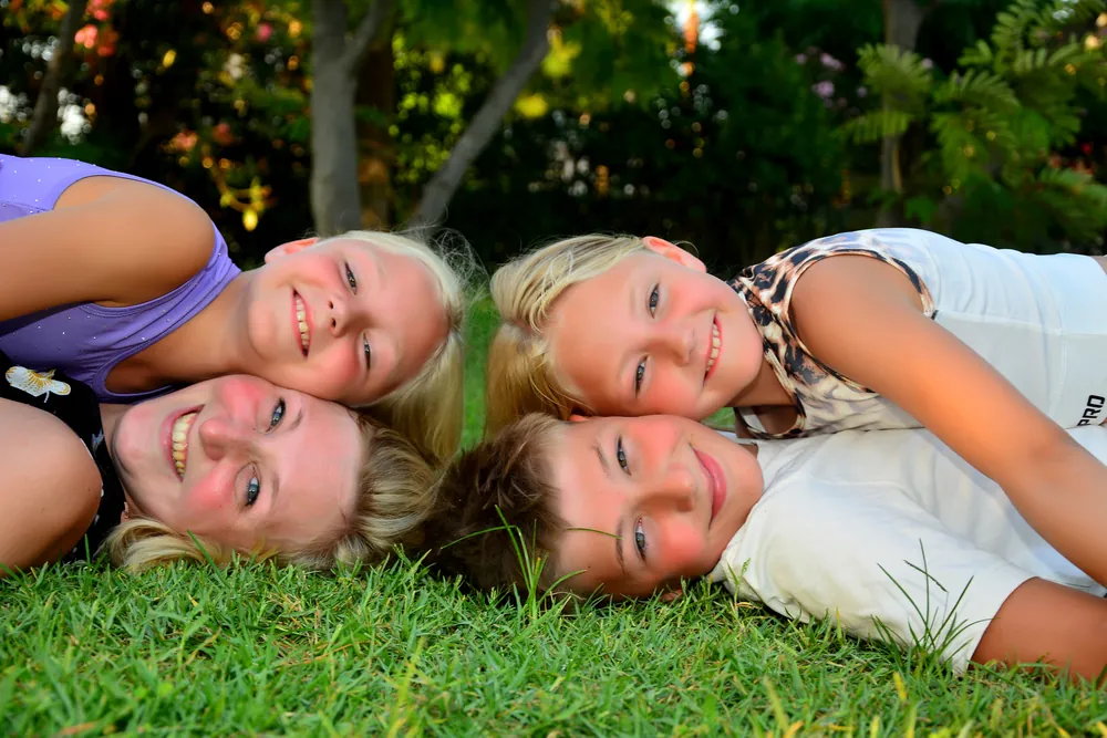 Mutter und drei Kinder Wange an Wange im Gras