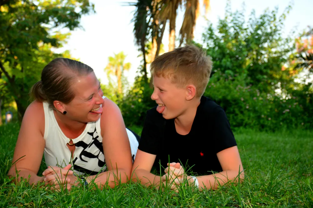 Mutter und Sohn liegen einander zugewandt im Gras
