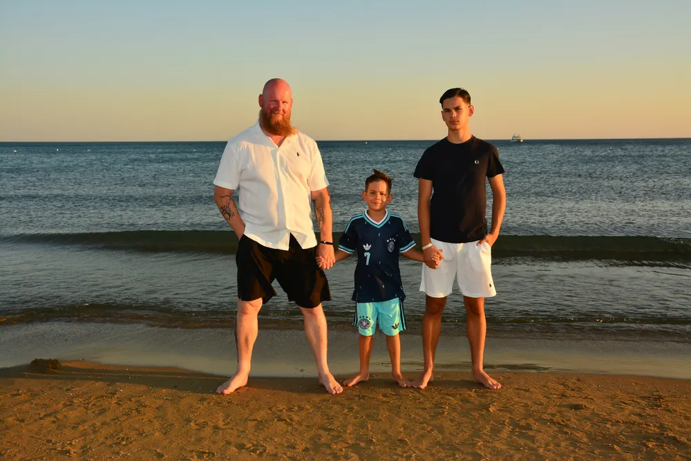 Vater und zwei Söhne stehen am Meer