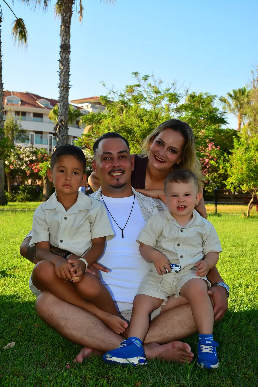 Familie zu viert im Gras unter Palmen