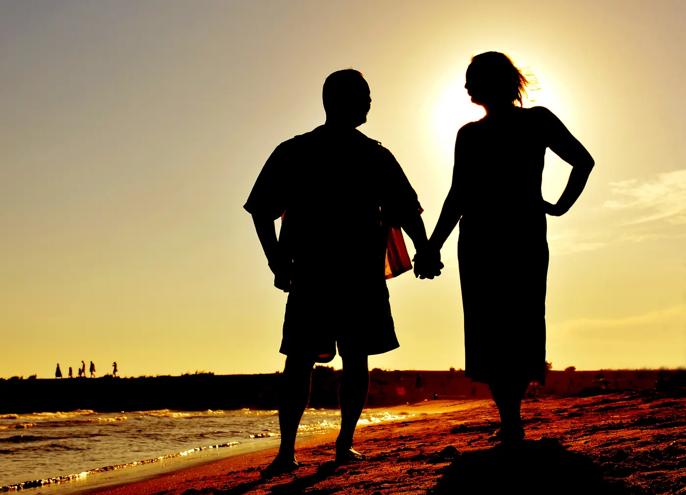 Paar Hand in Hand als Silhouette im Sonnenuntergang am Meer