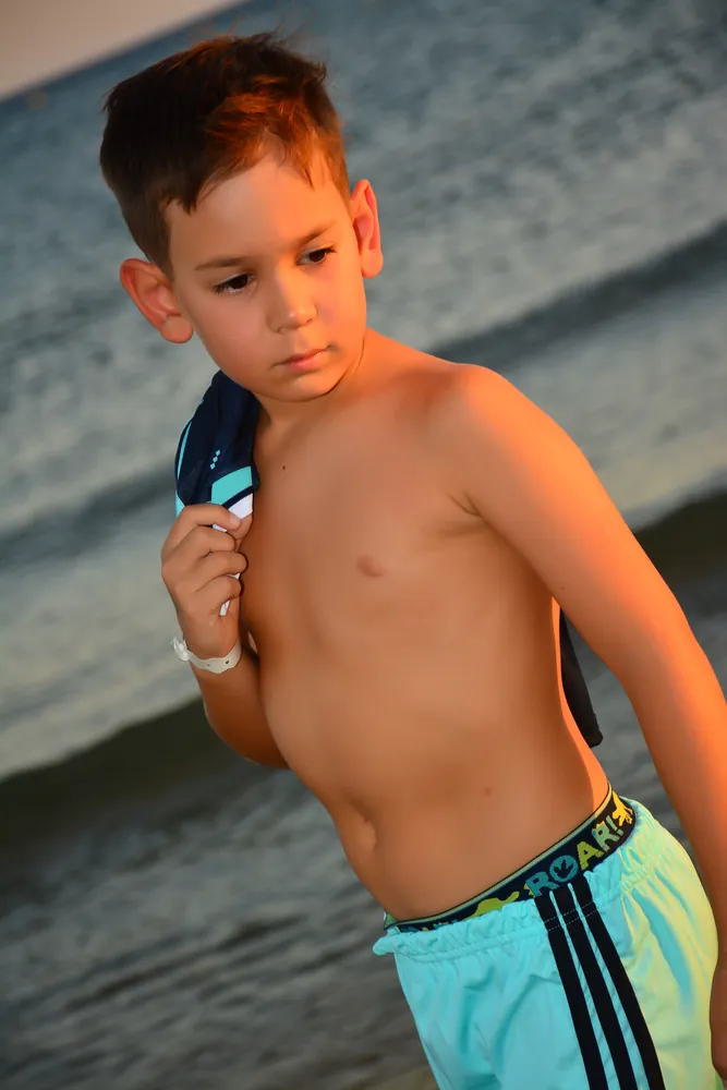 Junge mit Eis am Strand im Abendlicht