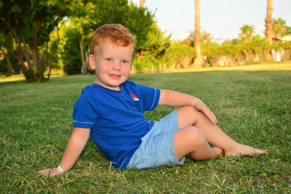 Kleiner Junge sitzt im Gras und lacht