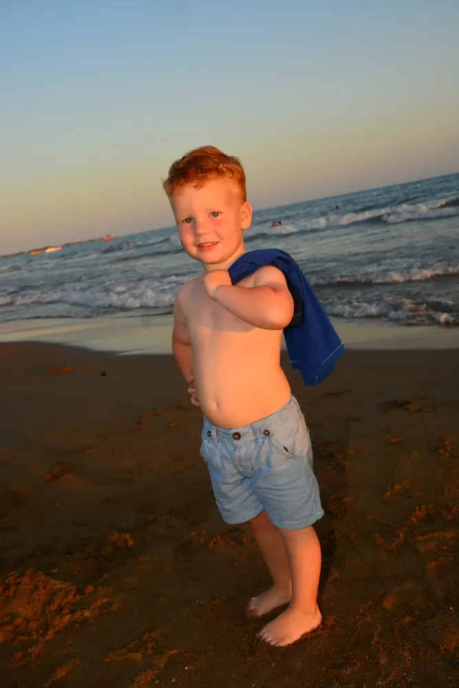 Junge am Wasser im Abendlicht, Hochformat