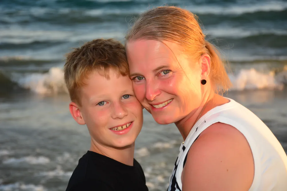 Mutter und Sohn Wange an Wange vor der Brandung